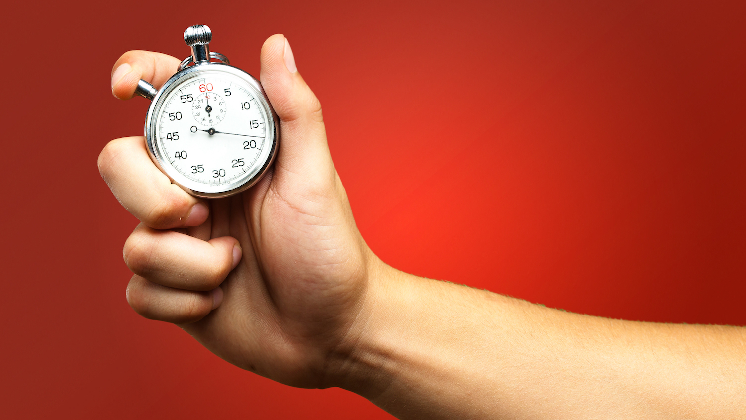 Close Up Of Hand Holding Stopwatch against a red background